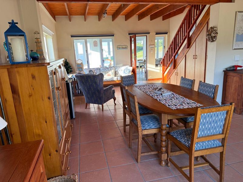 Open-plan living and dining area featuring exposed timber ceiling beams, terracotta floor tiles, and a timber staircase with integrated under-stair storage.