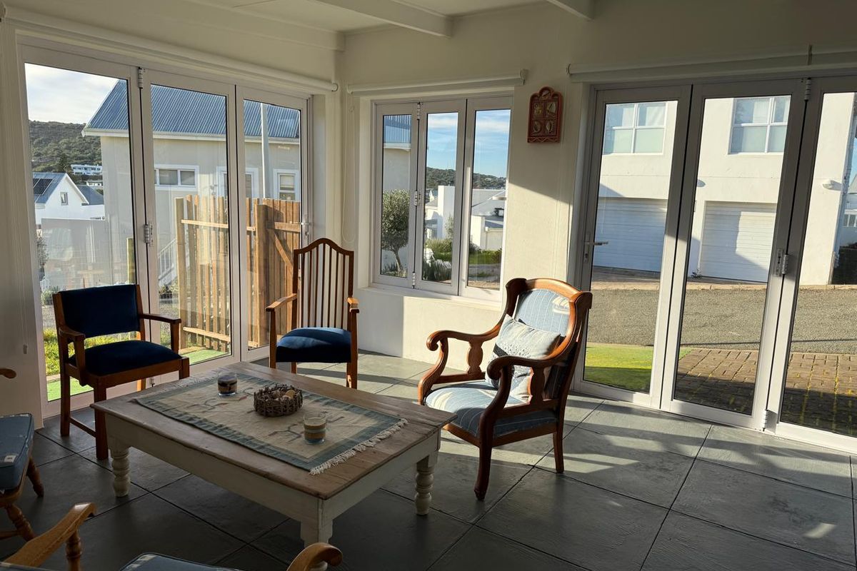 A bright, sunlit living area featuring large bi-fold doors, tiled flooring, and exposed ceiling beams, offering a seamless connection to the outdoor space.