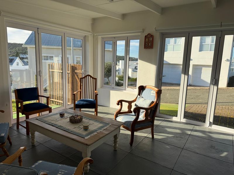 A bright, sunlit living area featuring large bi-fold doors, tiled flooring, and exposed ceiling beams, offering a seamless connection to the outdoor space.