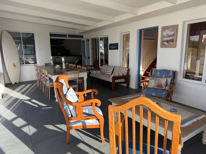 A spacious covered patio area featuring tiled flooring and exposed beam ceilings, providing a versatile outdoor living and dining space.