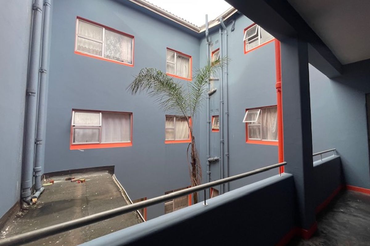 View of the building's rear courtyard area featuring blue exterior walls with orange trim, metal balustrades, and multiple casement windows.