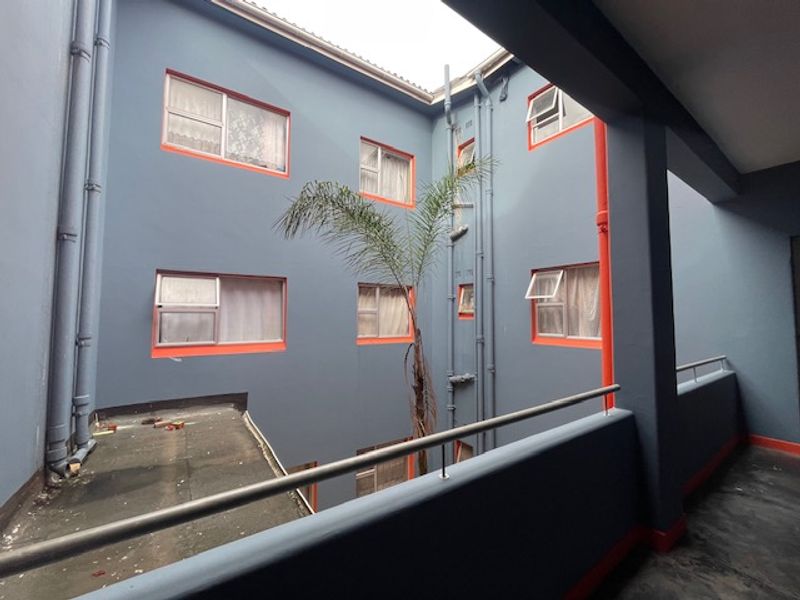 View of the building's rear courtyard area featuring blue exterior walls with orange trim, metal balustrades, and multiple casement windows.