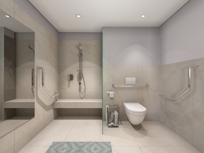 Modern accessible bathroom featuring a walk-in shower with built-in bench, wall-mounted toilet, and safety grab rails, finished with neutral floor-to-ceiling tiling.