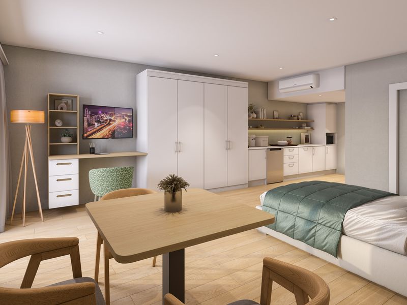 Modern open-plan studio apartment featuring a compact kitchenette, built-in storage cabinetry, light wood-look flooring, and integrated air conditioning.