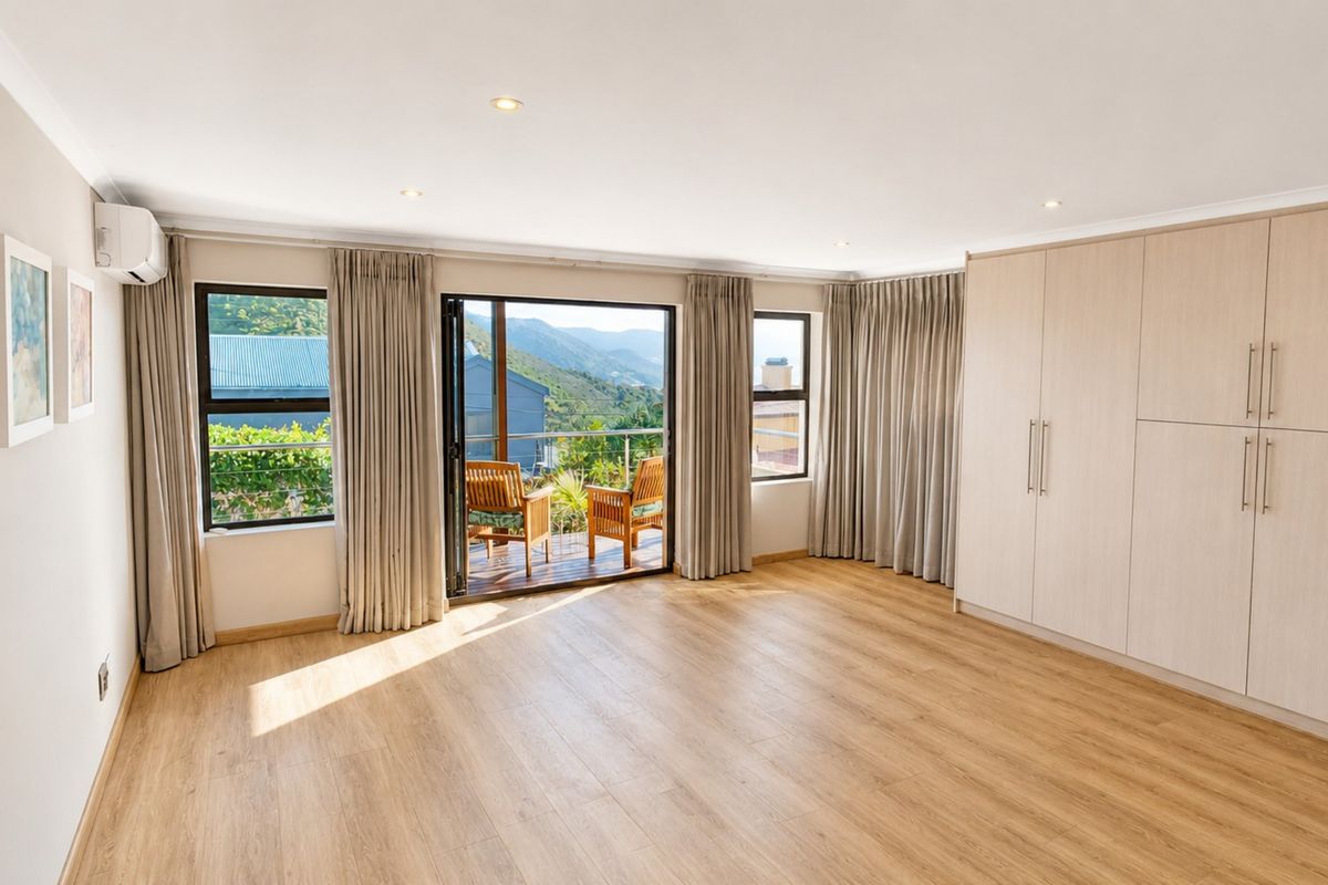 Spacious bedroom featuring light wood-look laminate flooring, extensive built-in cabinetry, recessed lighting, and sliding doors opening to a private balcony with scenic views.