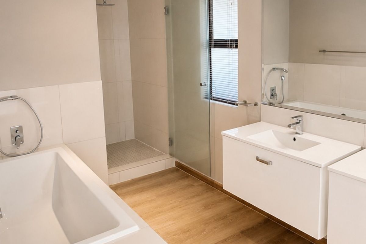 Modern, well-maintained bathroom featuring a built-in bathtub, separate walk-in shower with glass enclosure, and a sleek wall-mounted vanity with integrated basin.