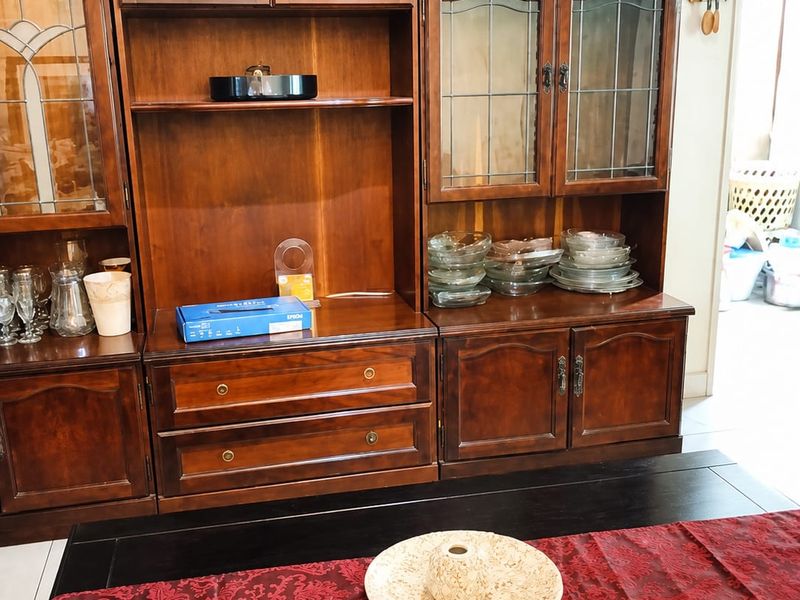 A dining area featuring a large, traditional built-in wooden display cabinet with glass-paneled doors and integrated storage drawers.