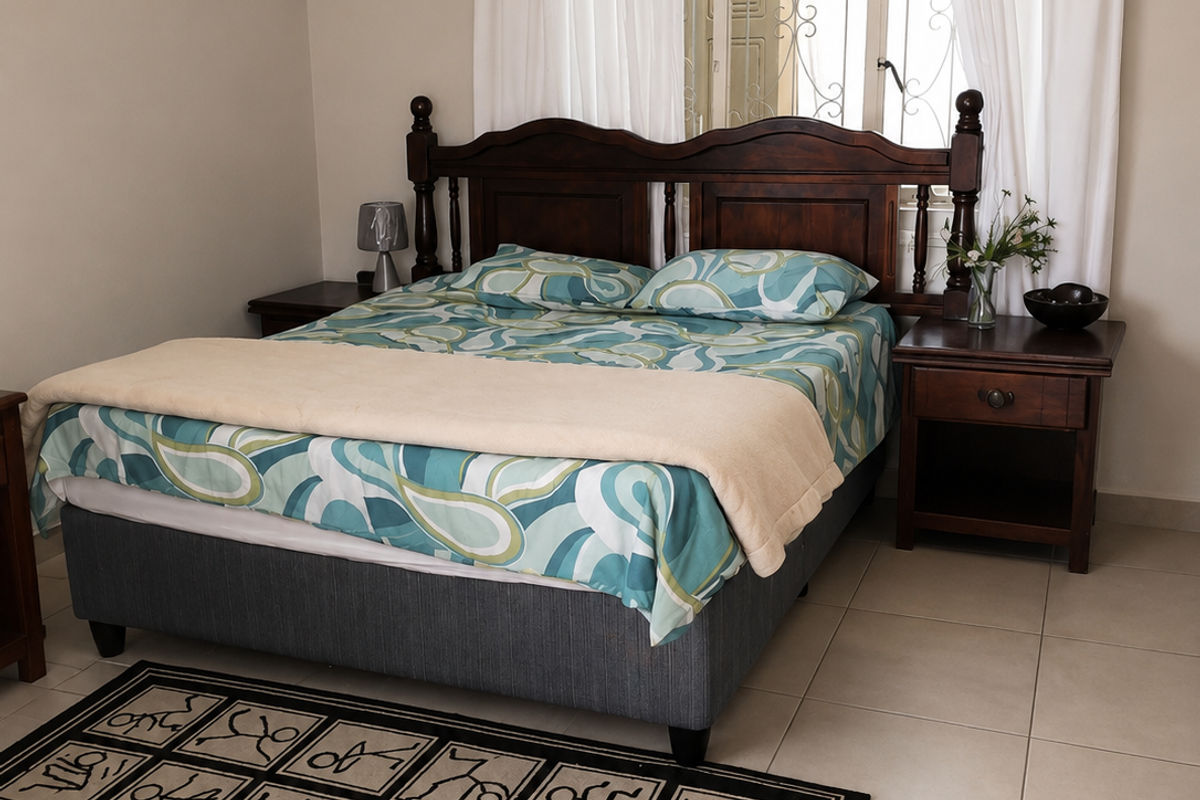 A bedroom featuring neutral wall tones, tiled flooring, and a window fitted with a security gate.