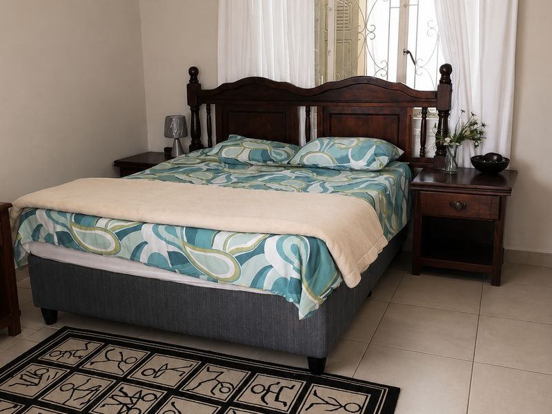 A bedroom featuring neutral wall tones, tiled flooring, and a window fitted with a security gate.