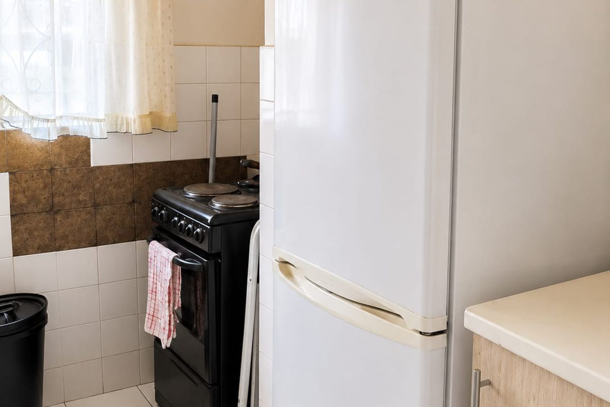 A functional kitchen featuring tiled flooring, a tiled splashback, a freestanding stove, and built-in cabinetry with laminate countertops.