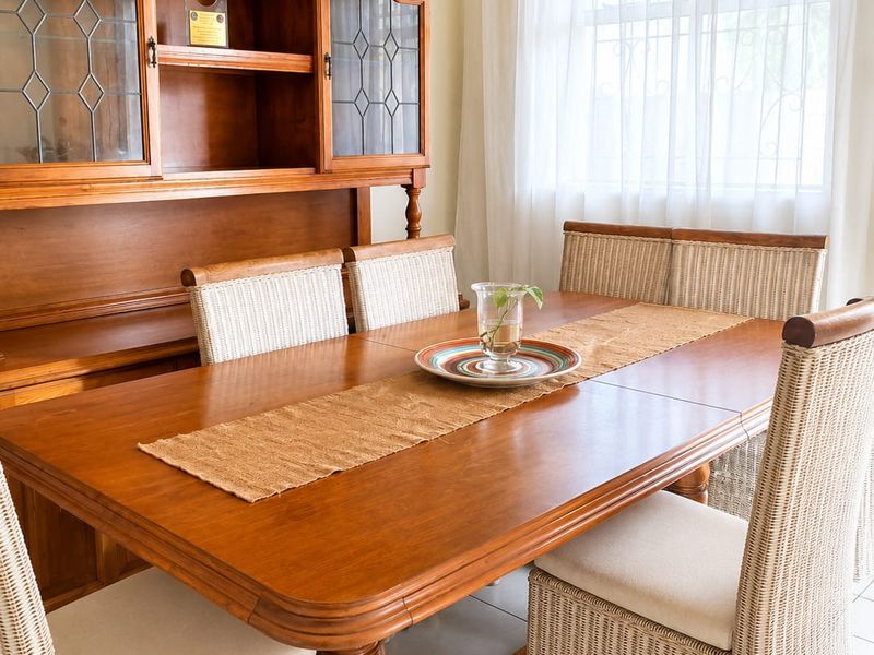 A dining room featuring tiled flooring and a window with security bars, providing a functional space for meals.