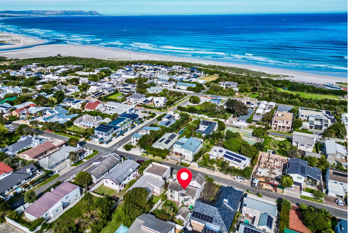 Aerial view of a coastal residential neighborhood showing the property location in relation to the beach and surrounding homes.