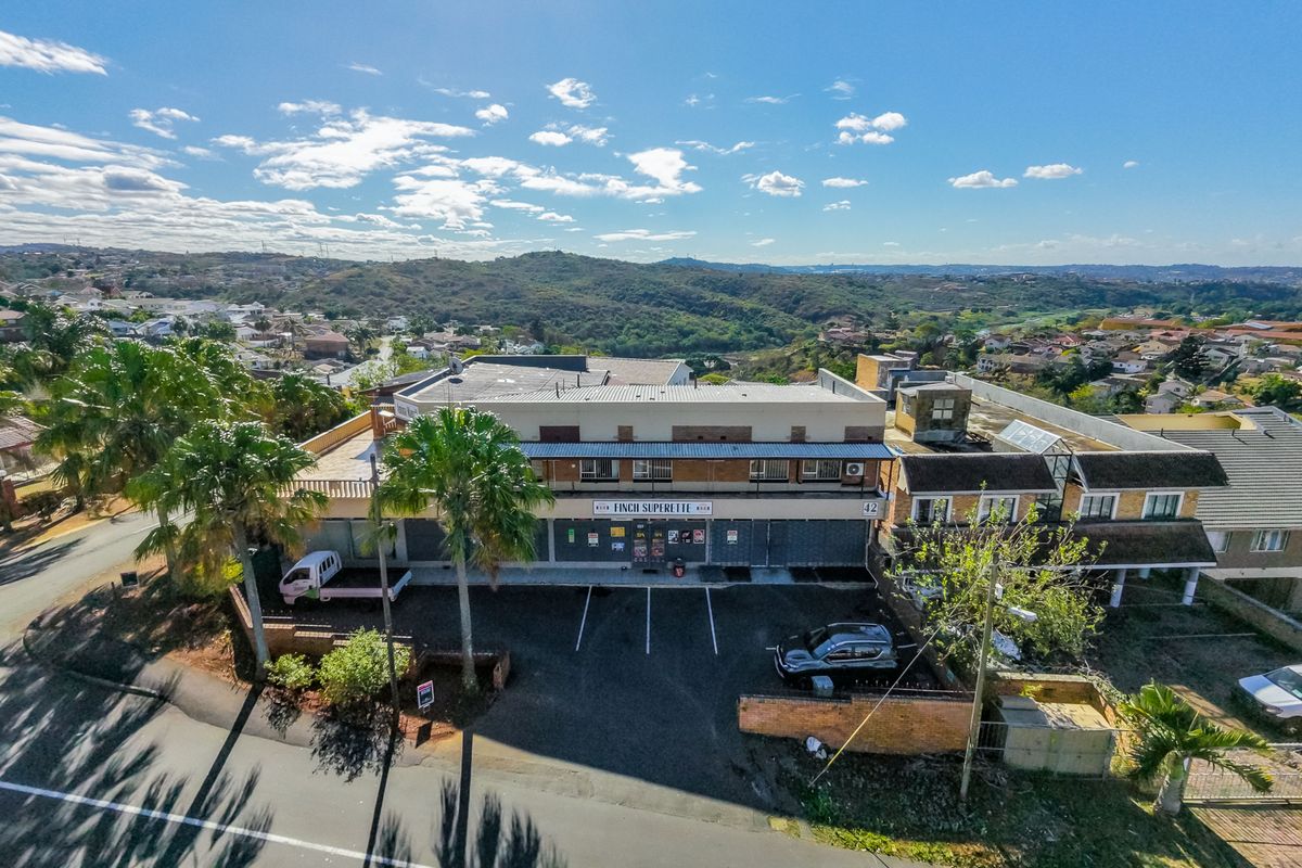 Aerial view of a commercial townhouse property featuring a storefront, paved parking area, and surrounding residential neighborhood.