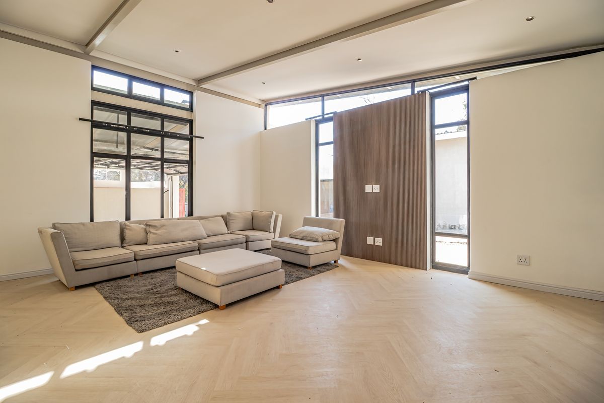 Spacious living room featuring high ceilings, herringbone timber flooring, a modern timber slat feature wall, and large black aluminium windows.