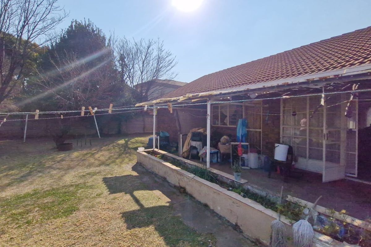 Rear view of the house featuring a tiled roof, a concrete patio area, and sliding glass doors leading into the home.