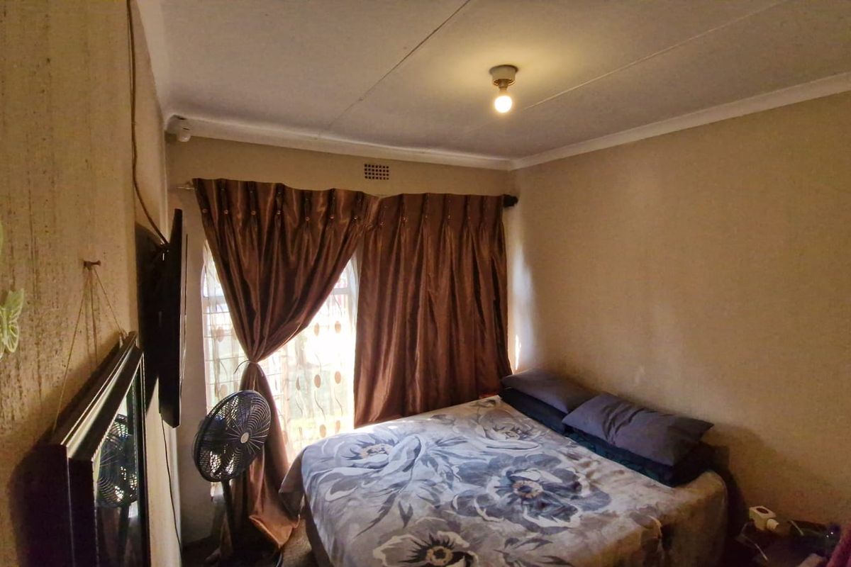 A compact bedroom featuring a window with curtain treatments and a standard ceiling finish.