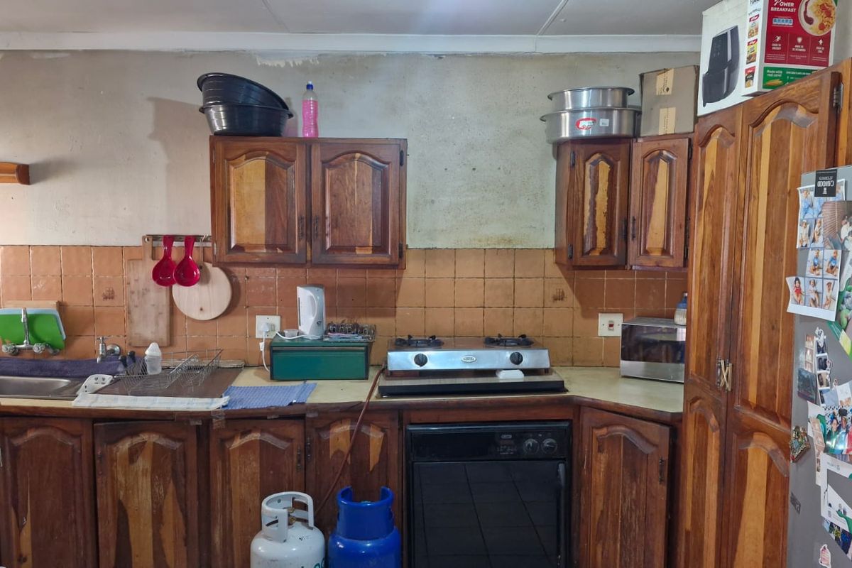 A dated kitchen featuring wooden cabinetry, a tiled backsplash, and integrated cooking appliances, offering significant potential for modernization and aesthetic improvement.