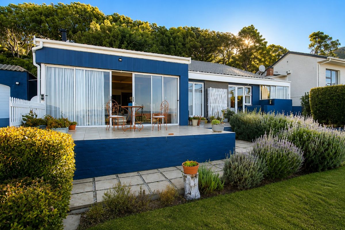 Rear view of the property featuring a tiled patio, large sliding glass doors, and a well-maintained landscaped garden.