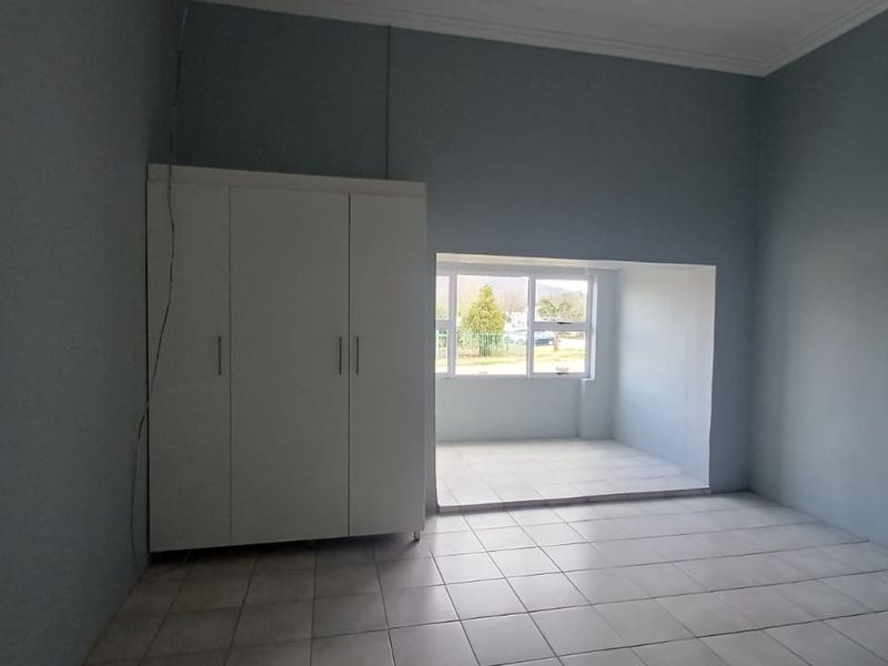 A spacious, empty bedroom featuring neutral tiled flooring, built-in wardrobe storage, and a recessed window area providing natural light.