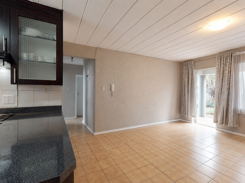 Open plan kitchen and living area featuring tiled flooring, built-in cabinetry, and direct access to an outdoor patio space.