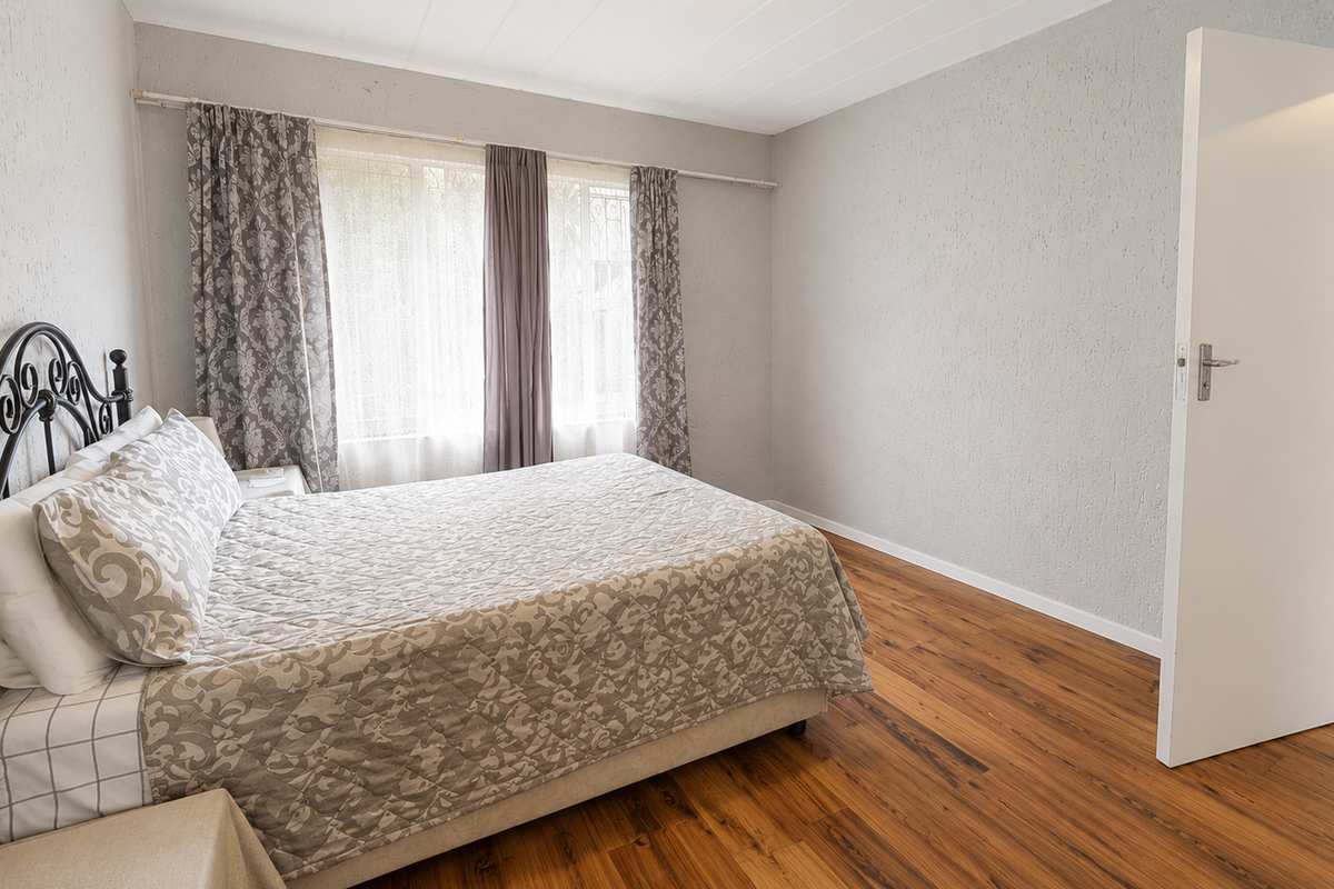 A bedroom featuring laminate flooring and textured walls, offering a neutral base for personalization.