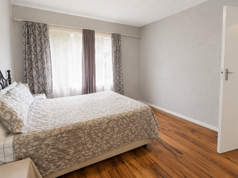 A bedroom featuring laminate flooring and textured walls, offering a neutral base for personalization.