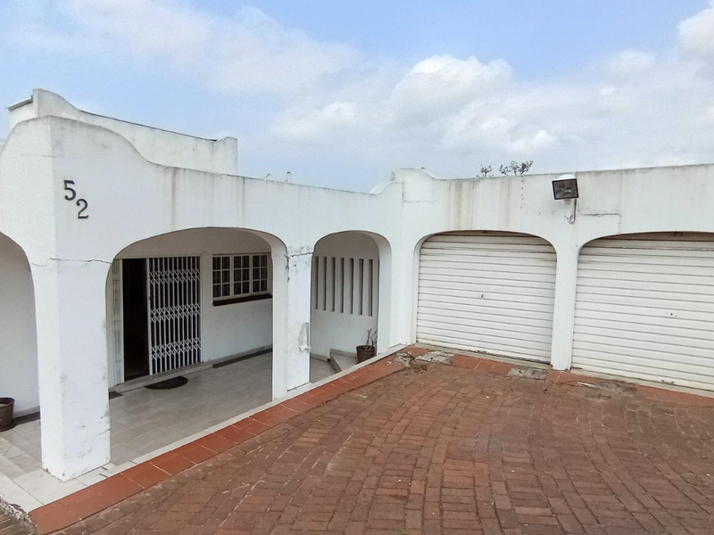 Front elevation of a house featuring a double garage, brick paved driveway, and a covered entrance with architectural archways.