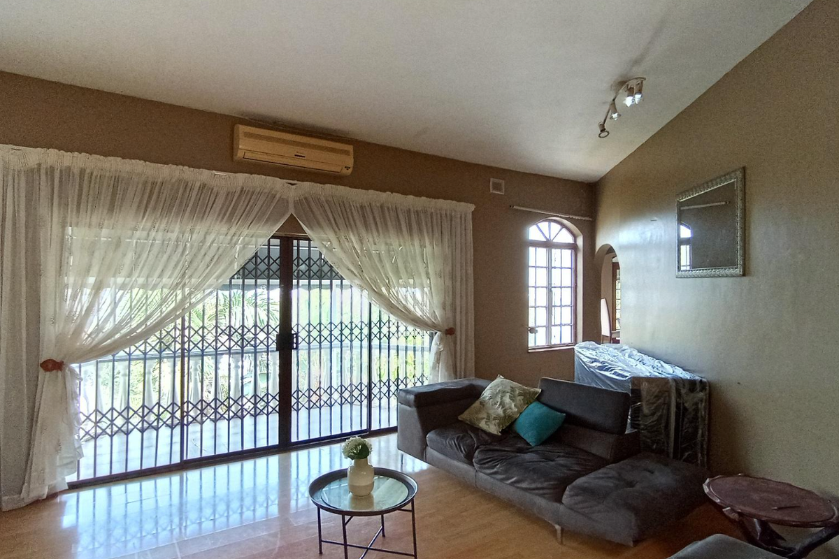 Spacious living room featuring tiled flooring, a split-system air conditioner, and large sliding glass doors with security gates leading to an outdoor area.