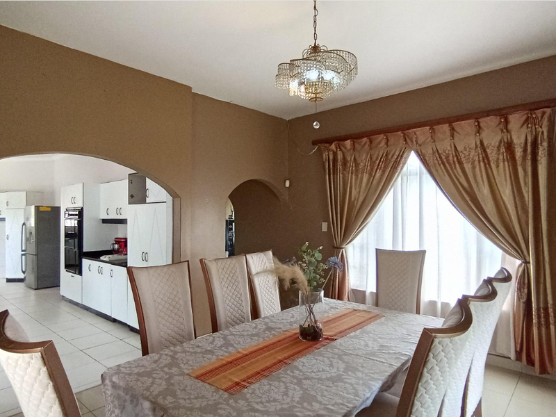 Open plan dining area featuring an arched transition to a functional kitchen with built-in cabinetry and tiled flooring.