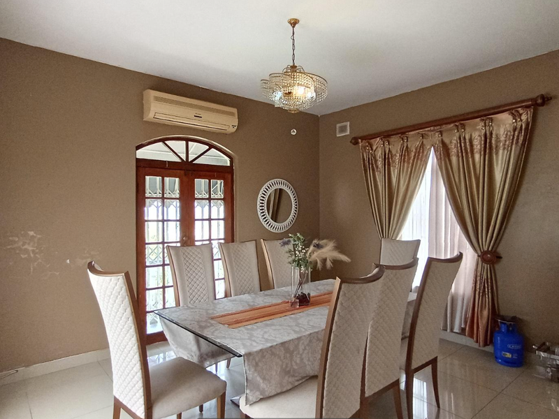 Dining room featuring tiled flooring, a crystal chandelier, split-system air conditioning, and a wall-mounted basin, with access to an outdoor area via arched doors.