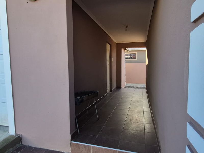 A covered outdoor patio area featuring tiled flooring, adjacent to the garage entrance, providing a functional transition space.