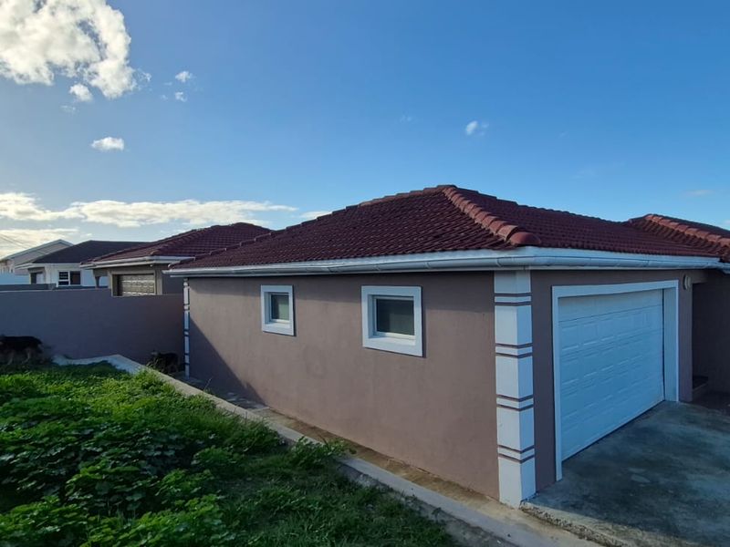 Front exterior view of the property featuring a tiled roof, single garage, and paved driveway with surrounding boundary wall.