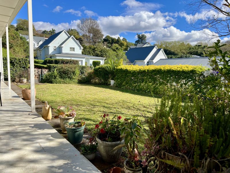 A covered concrete patio overlooking a well-maintained garden with established hedging and surrounding residential views.