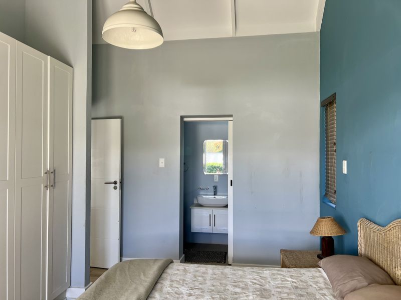 Bedroom featuring a built-in wardrobe and an adjoining en-suite bathroom with a vanity basin.