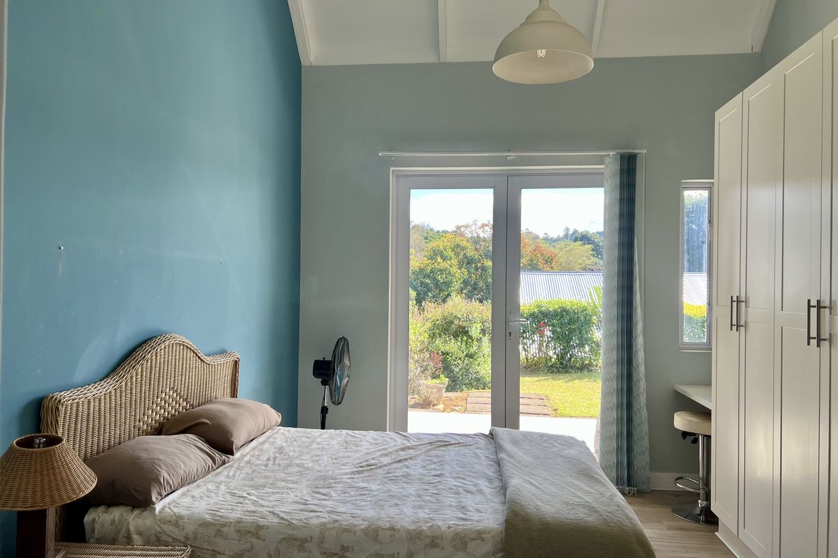 Bright bedroom featuring a vaulted ceiling, built-in wardrobe, and French doors providing direct access to the garden.