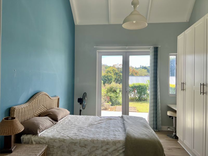 Bright bedroom featuring a vaulted ceiling, built-in wardrobe, and French doors providing direct access to the garden.