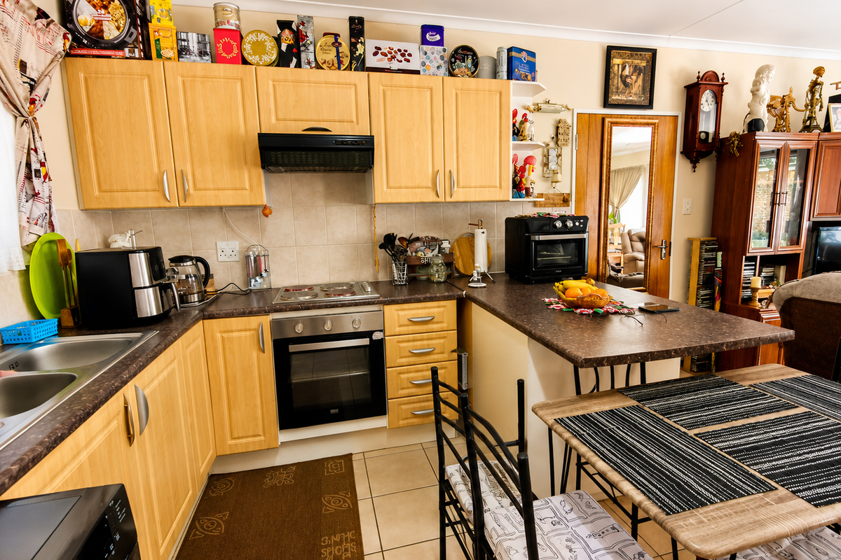 Functional kitchen featuring light wood cabinetry, laminate countertops, integrated oven and hob, and a breakfast bar area with tiled flooring.