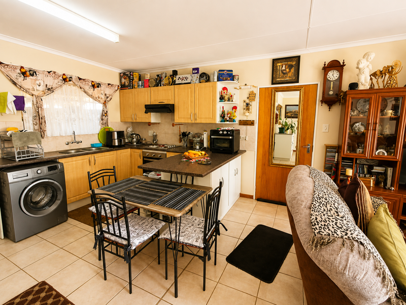 Open-plan kitchen and dining area featuring light wood cabinetry, tiled flooring, and integrated cooking appliances.