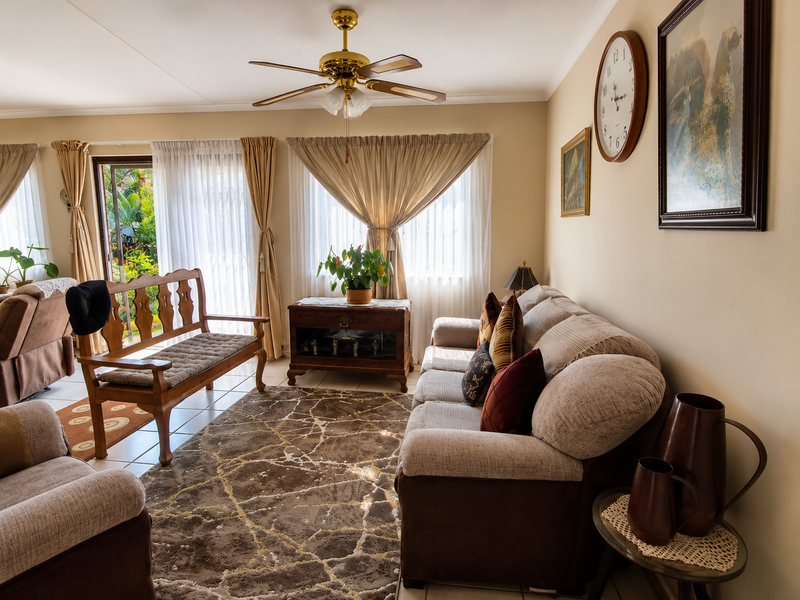 A comfortable living room featuring tiled flooring, a ceiling fan, and a sliding glass door providing access to the outdoor area.