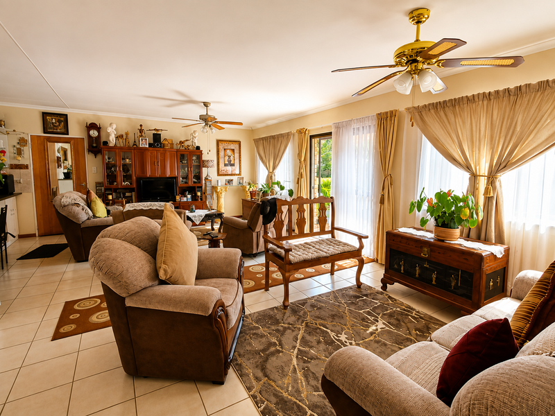 Spacious living room featuring tiled flooring, dual ceiling fans, and large sliding glass doors that provide access to the outdoor area.