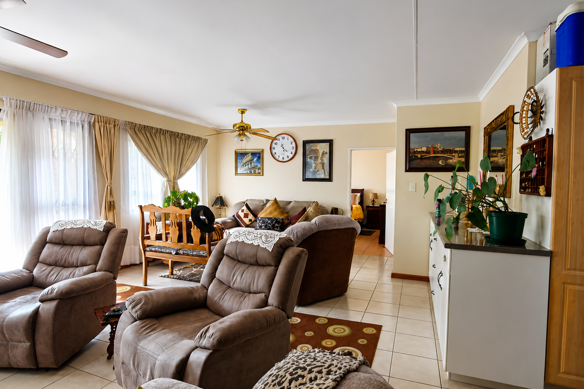 A spacious living room featuring tiled flooring, ceiling fans, and neutral wall tones, offering a comfortable and functional layout for relaxation.