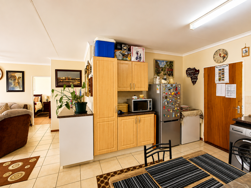 Open-plan living and kitchen area featuring light wood cabinetry, tiled flooring, and functional layout connecting to adjacent bedroom space.