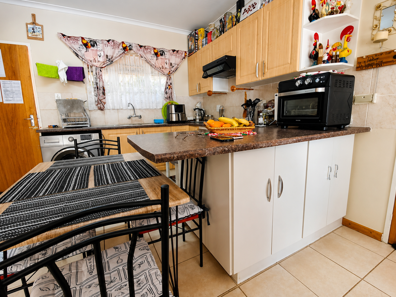 A functional kitchen featuring laminate cabinetry, tiled backsplash, and ceramic flooring, offering a practical layout with an integrated breakfast bar area.
