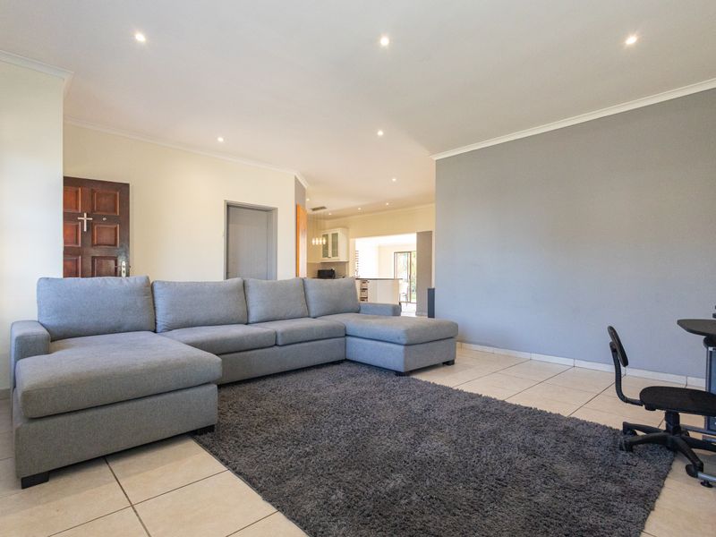 Spacious open-plan living area featuring neutral tiled flooring, recessed downlighting, and a seamless flow towards the kitchen and dining space.