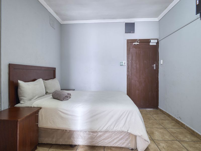 A functional bedroom featuring tiled flooring and neutral wall finishes, providing a simple and practical sleeping space.