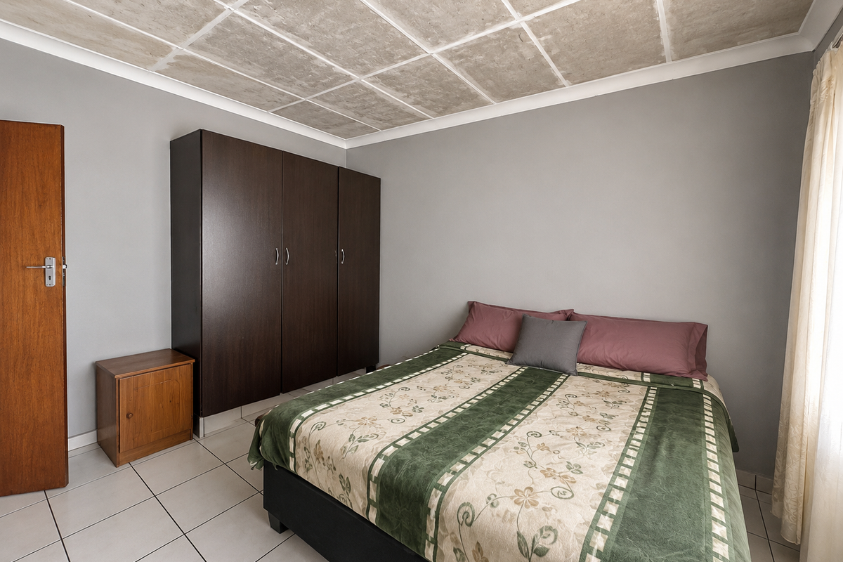 A bedroom featuring tiled flooring, a built-in wardrobe, and a textured ceiling finish, providing a functional space for rest.