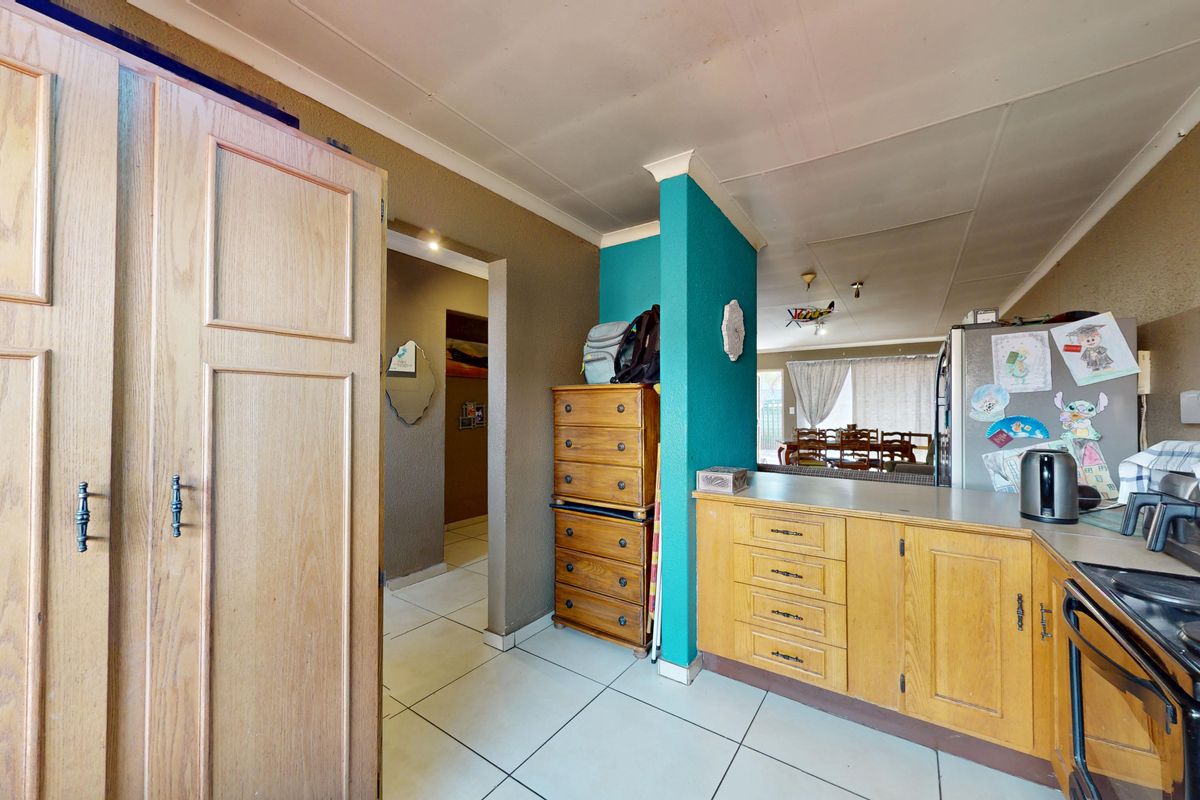 A functional kitchen area featuring built-in wooden cabinetry, tiled flooring, and an electric hob, offering potential for modernization and aesthetic updates.