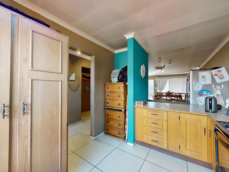A functional kitchen area featuring built-in wooden cabinetry, tiled flooring, and an electric hob, offering potential for modernization and aesthetic updates.