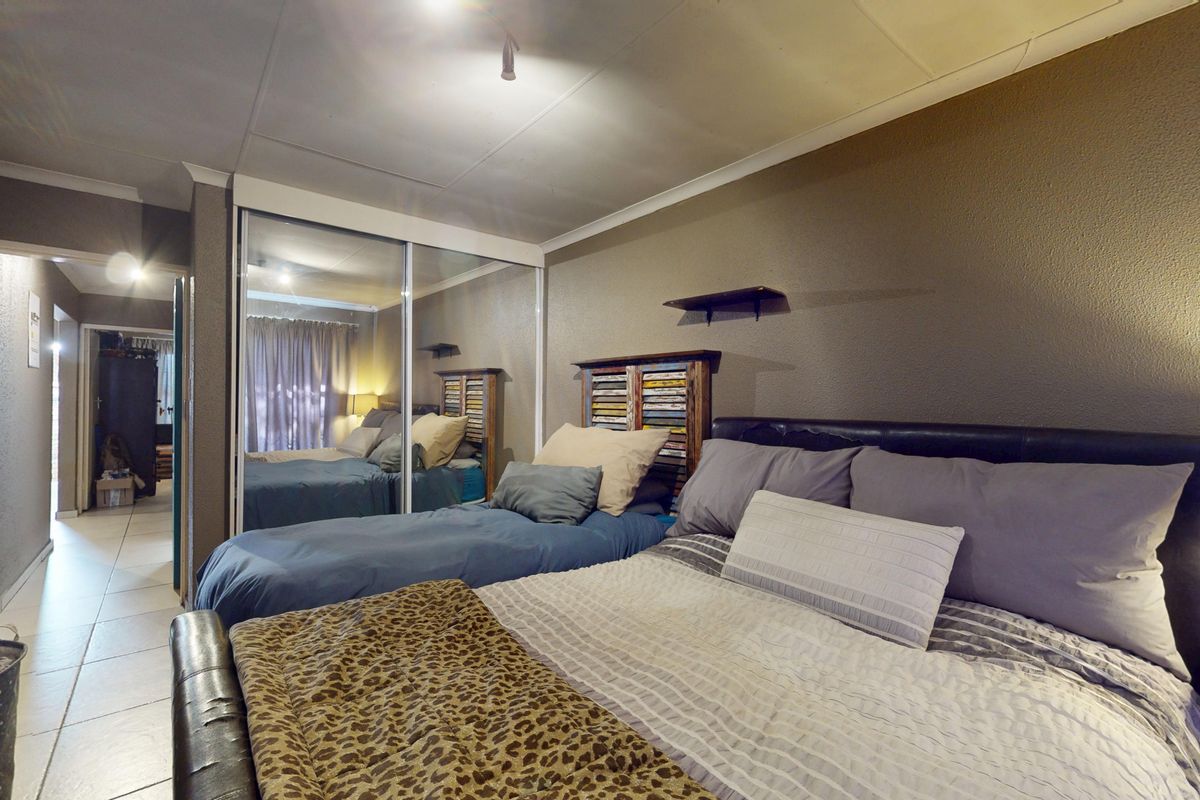 A bedroom featuring tiled flooring, a coved ceiling, and built-in mirrored sliding wardrobe doors, providing ample storage and a functional layout.