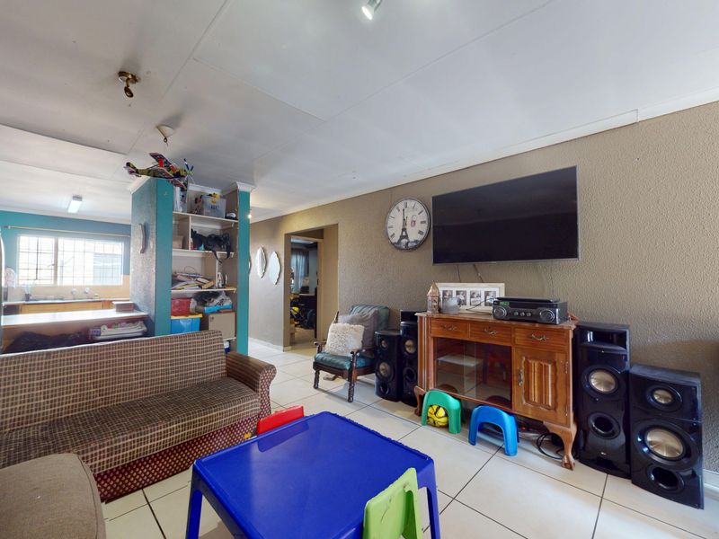 Open plan living area featuring tiled flooring and a built-in shelving unit, connecting to the kitchen space.